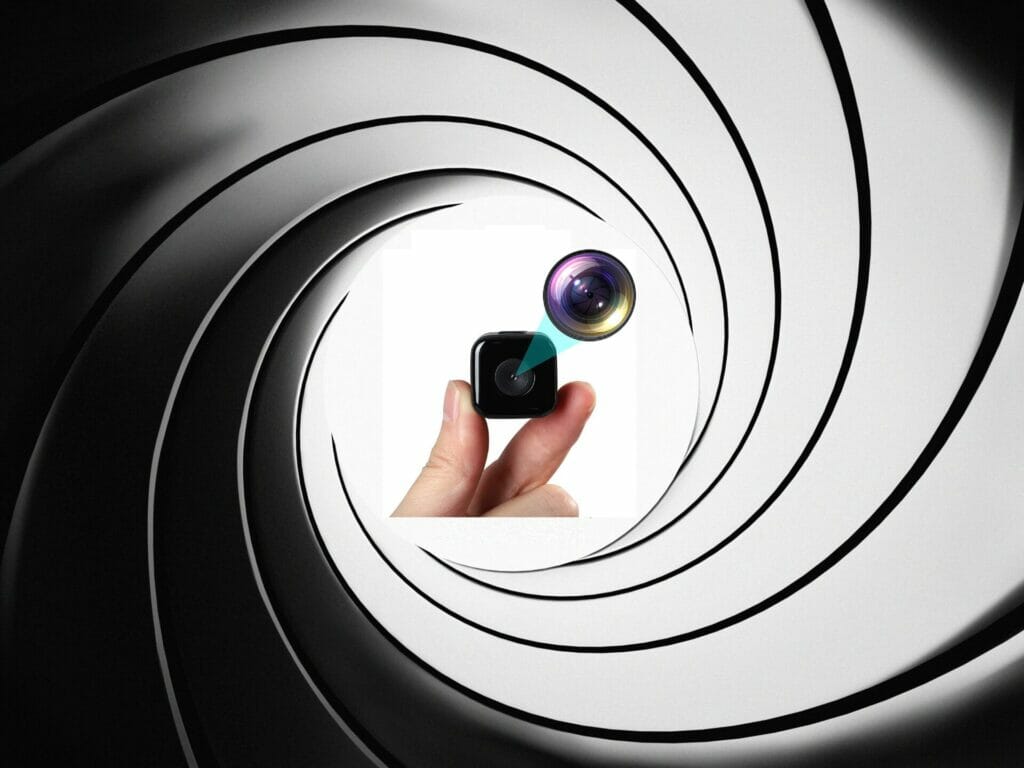 A person holding a discreet camera in a black and white circle.