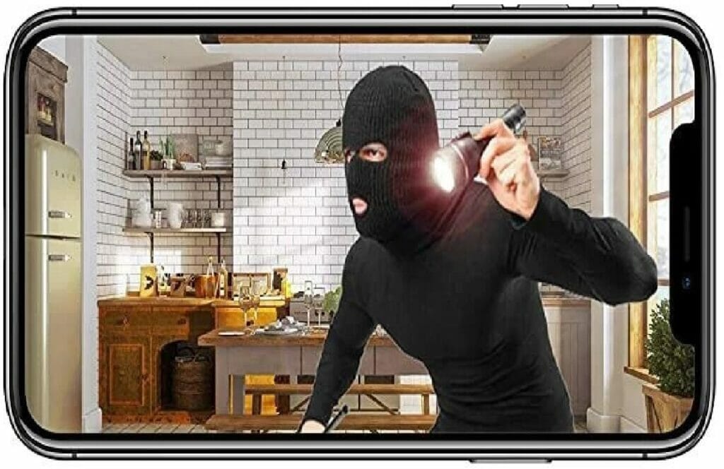 A man in a black mask is holding a knife in a kitchen, captured by a discreet surveillance camera.