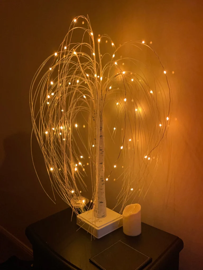A white tree with fairy lights on a table.